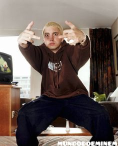 a young man sitting on top of a bed giving the thumbs up