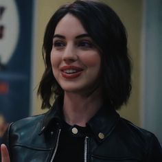 a close up of a person wearing a leather jacket and giving the thumbs up sign