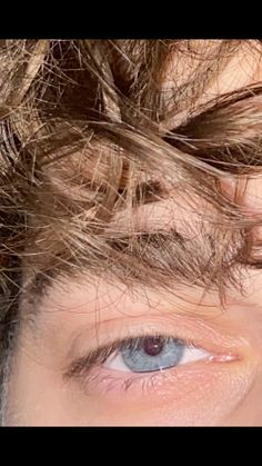 a close up of a person's face with hair blowing in the wind and blue eyes