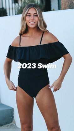 a woman in a black one piece swimsuit posing for the camera with her hands on her hips