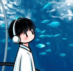 a boy with headphones is looking at fish in the water