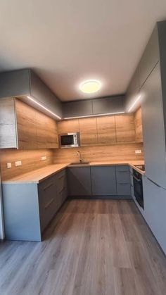 an empty kitchen with wood flooring and stainless steel appliances