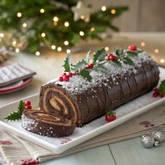 a chocolate roll on a plate with holly decorations