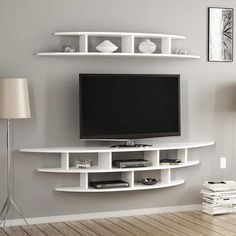 a flat screen tv sitting on top of a white shelf next to a wall mounted television