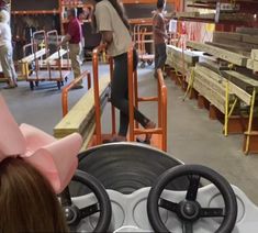 a woman wearing a pink hat standing in front of an assembly line at a factory