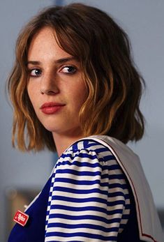 a close up of a person wearing a blue and white striped shirt with short hair