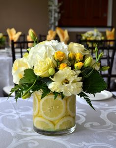 a vase filled with yellow and white flowers on top of a table covered in plates