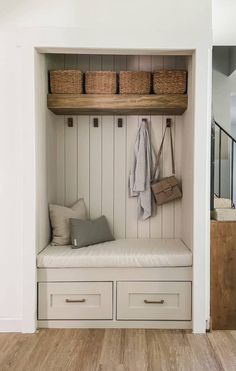 a white bench with two baskets on top of it and a coat rack above the bench