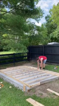 two people working on building a wooden deck in the yard with wood boards laid out around them