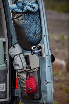 the back end of a blue van with luggage in it's cargo compartment and an open door