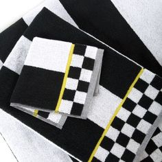 three black and white towels are laying next to each other on a table with yellow trim