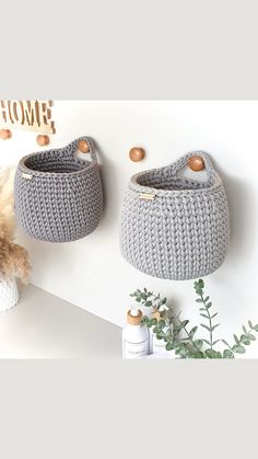 two crocheted baskets hanging on the wall next to a stuffed animal and plant