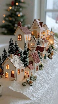 a christmas village with lit up houses and trees in the snow on a window sill