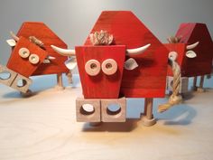 three wooden toy cows with faces on them