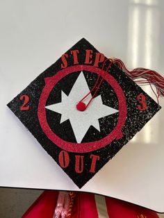 a black and red graduation cap with the words step out on it