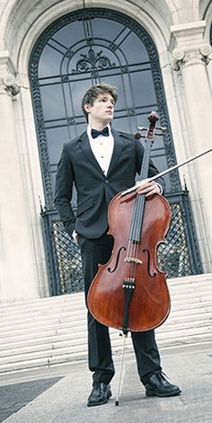 a man in a tuxedo holding a cello