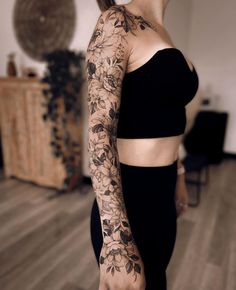 a woman with a tattoo on her arm and shoulder is standing in a room full of wood flooring