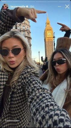 two beautiful young women standing next to each other in front of the big ben clock tower