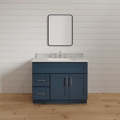 a bathroom vanity with a mirror above it on the wall next to a wooden floor