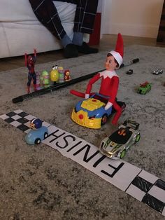 an elf is sitting on top of a toy car in the middle of a race track