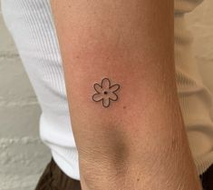 a woman's arm with a small flower tattoo on the left side of her arm