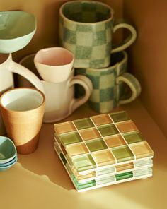 there are many cups and plates on the shelf together, including one with a mosaic design