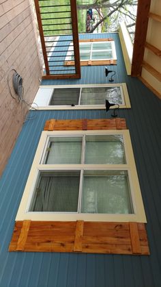 two windows on the side of a building with wood trimmings and blue siding