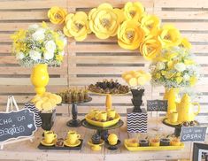 a table topped with lots of yellow flowers and plates filled with desserts on top of it