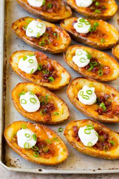 baked potato skins with sour cream and chives on a baking sheet, ready to be eaten