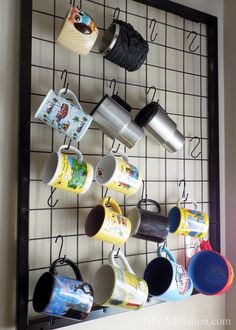 coffee cups are hanging on the wall with hooks