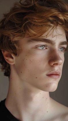 a young man with freckled hair and blue eyes looks at the camera while wearing a black shirt