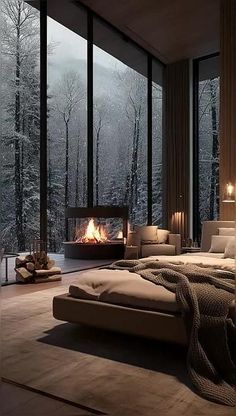 a bedroom with a fireplace in the middle and lots of windows on both sides that look out onto trees