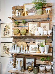 a shelf filled with vases and pictures on top of wooden shelves in a room