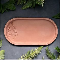 a clay tray with fern leaves around it