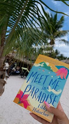 a person holding up a book in front of a palm tree and the words meet me in paradise