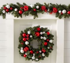 a christmas wreath hanging on the front door with red and white baubles around it