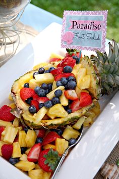 a pineapple fruit salad with blueberries and strawberries in it on a white plate