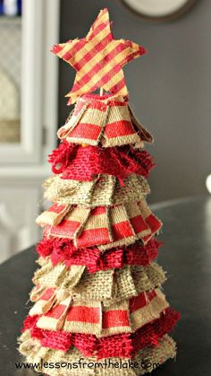 a christmas tree made out of burlock and ribbon on a table with a clock in the background