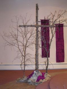 a wooden cross sitting on top of a floor next to a pile of cloths