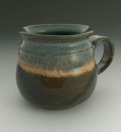 a brown and green ceramic pitcher with handle