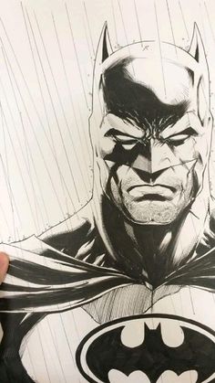 a hand holding up a drawing of batman