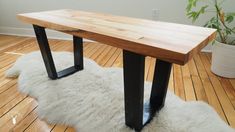 a wooden bench sitting on top of a hard wood floor next to a white rug