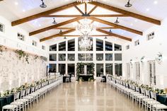 an indoor wedding venue with white chairs and chandeliers