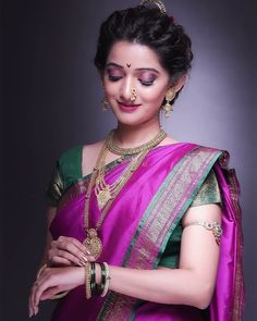 a woman in a purple and green saree with gold jewelry on her neck, wearing a