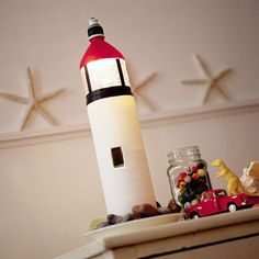 a red and white light house sitting on top of a table next to toy cars