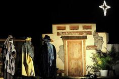 three mannequins dressed in costumes stand outside the front door of a building at night