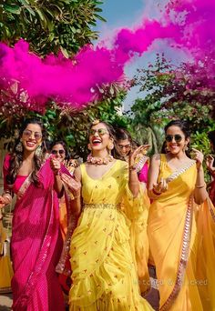 several women in yellow and pink dresses are throwing colored powder on each other as they walk down the street