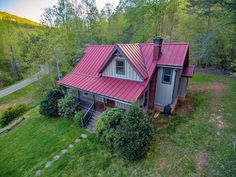 an aerial view of a small cabin in the woods with a red roof and stairs leading up to it