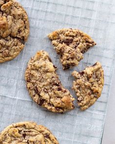 chocolate chip cookies on top of a piece of parchment paper with one broken in half