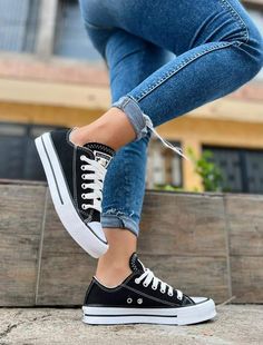 a woman in black and white converse sneakers is standing on the steps with her legs crossed